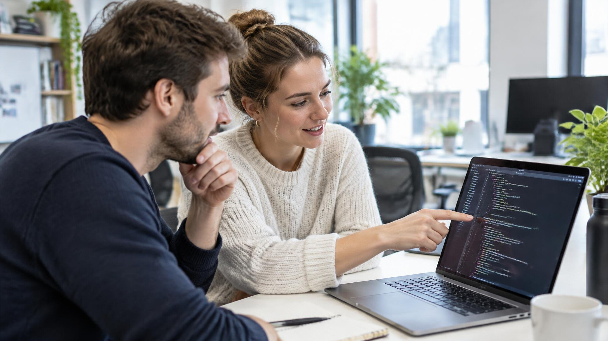 Two people looking together at a laptop screen with code